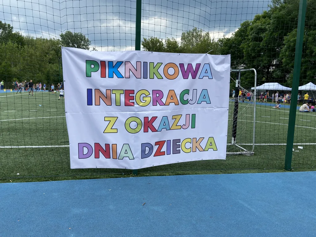 Banner wiszący przy wejściu na boisko szkolne. Napis na bannerze: Piknikowa integracja z okazji Dnia Dziecka