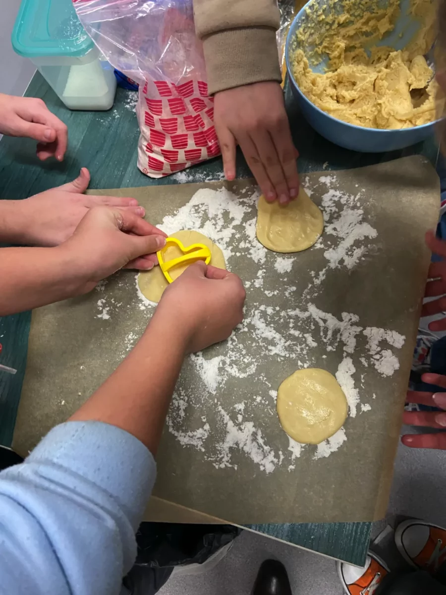Uczniowe z pomocą foremek wycinają z ciasta różne kształty - w tym przypadku ciastko będzie miało kształt serduszka.