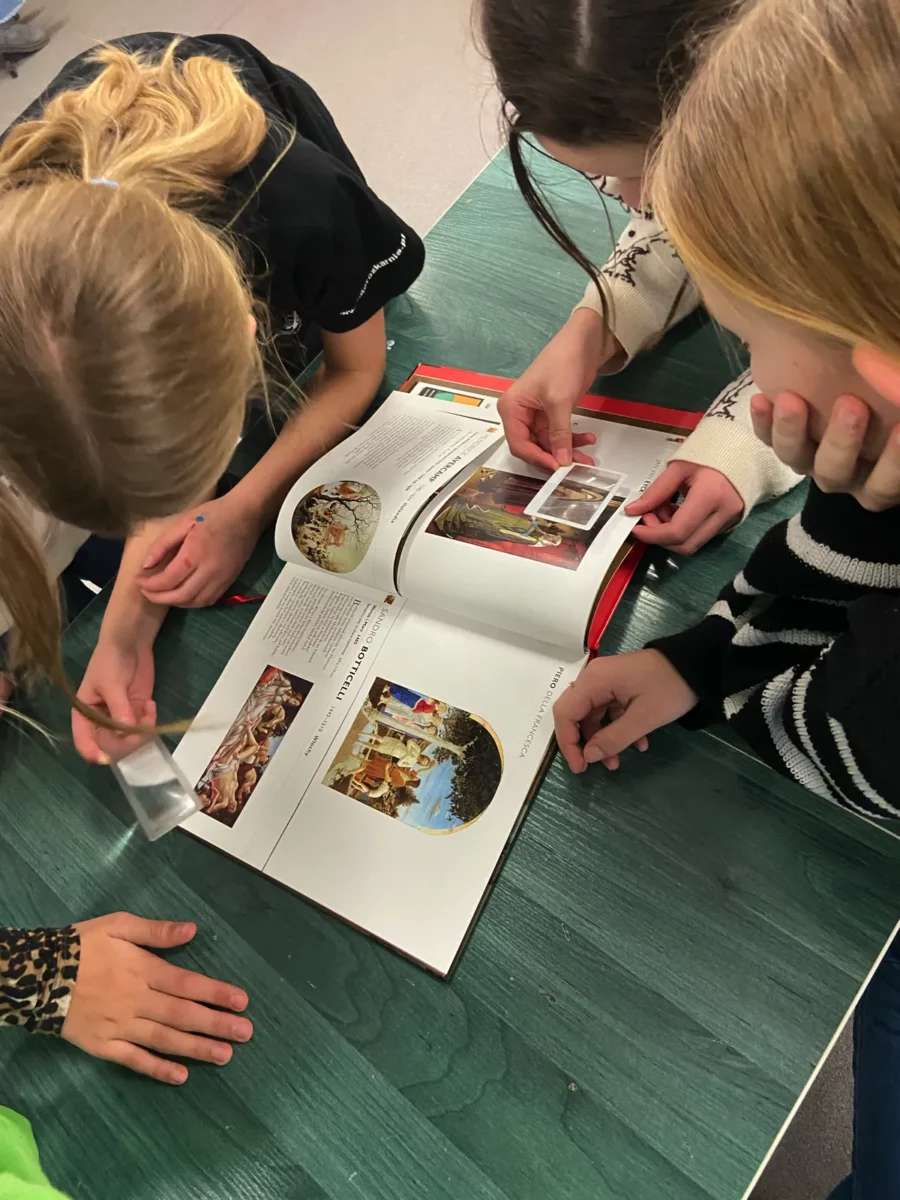 Zabawne koło - dzieci pochylone nad książką, oglądają przez lupki wydrukowane w książce obrazy.