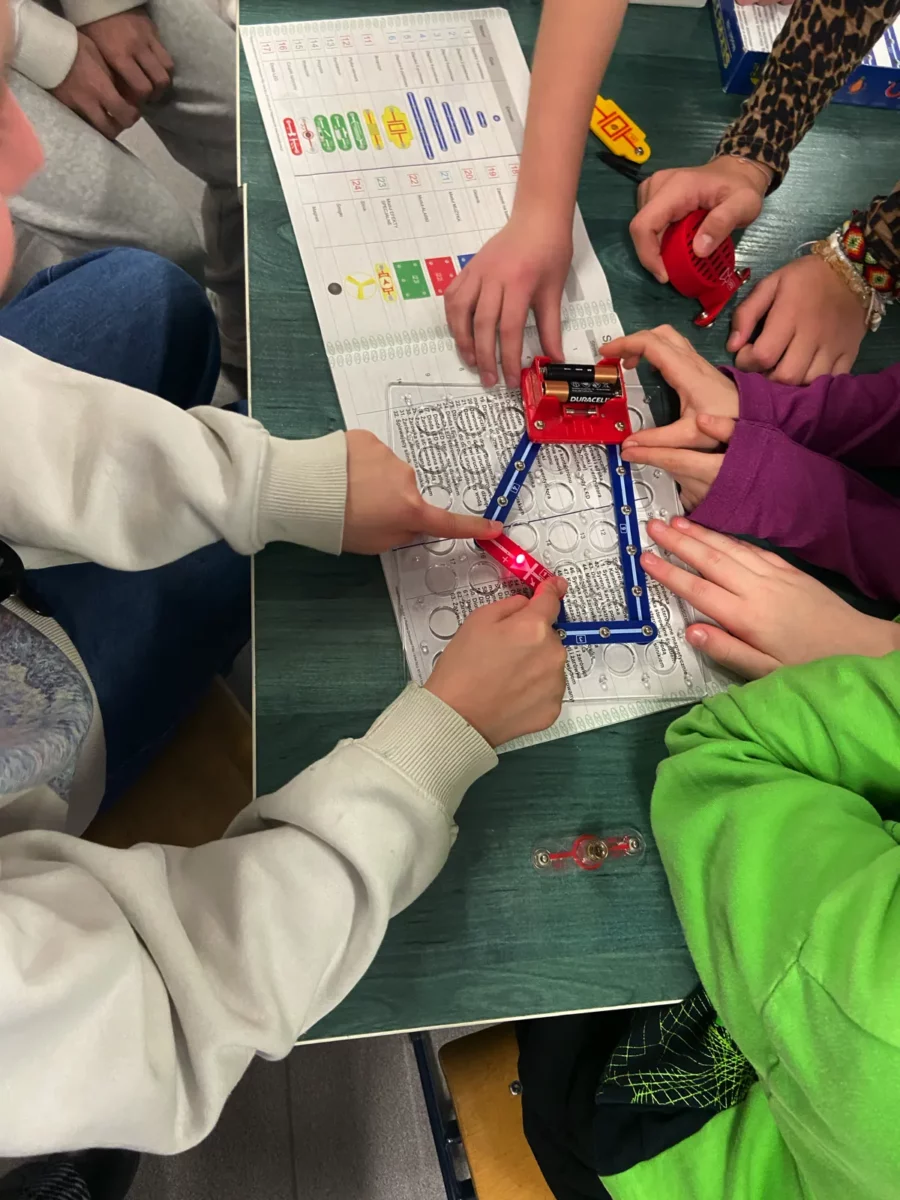 Ta sama grupa uczniów z układem elektrycznym. Tym razem, w miejsce żarówki podłączona jest dioda świecąca.